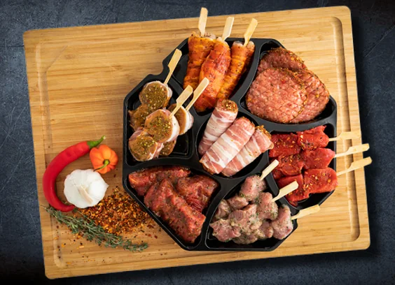 Gourmetschaal met vleesvakjes op een houten plank