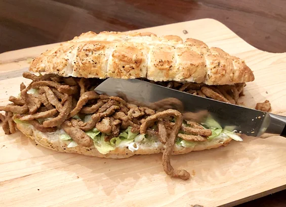 Shoarmabroodje met reepjes vlees en sla op een plank